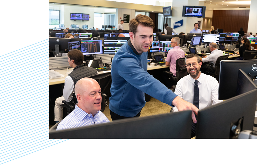 Three Silver Lakeassociates looking at computer monitors on the trading floor