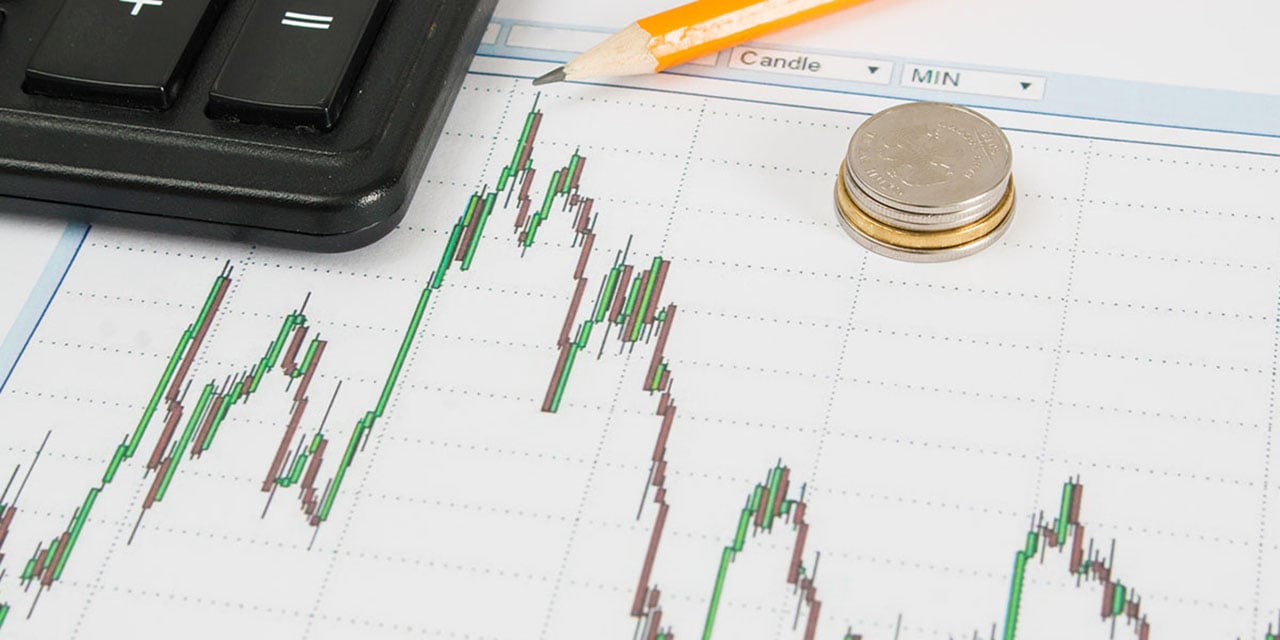 Graph paper with a line graph, a pencil, a keyboard and a stack of coins.